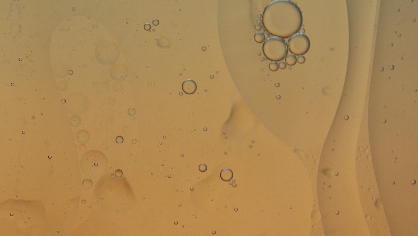 Macro of a hydrating serum texture with suspended droplets in warm golden light