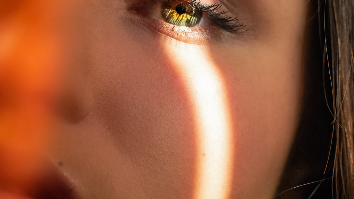 Close-up of a woman face with a stripe of warm light across her cheek