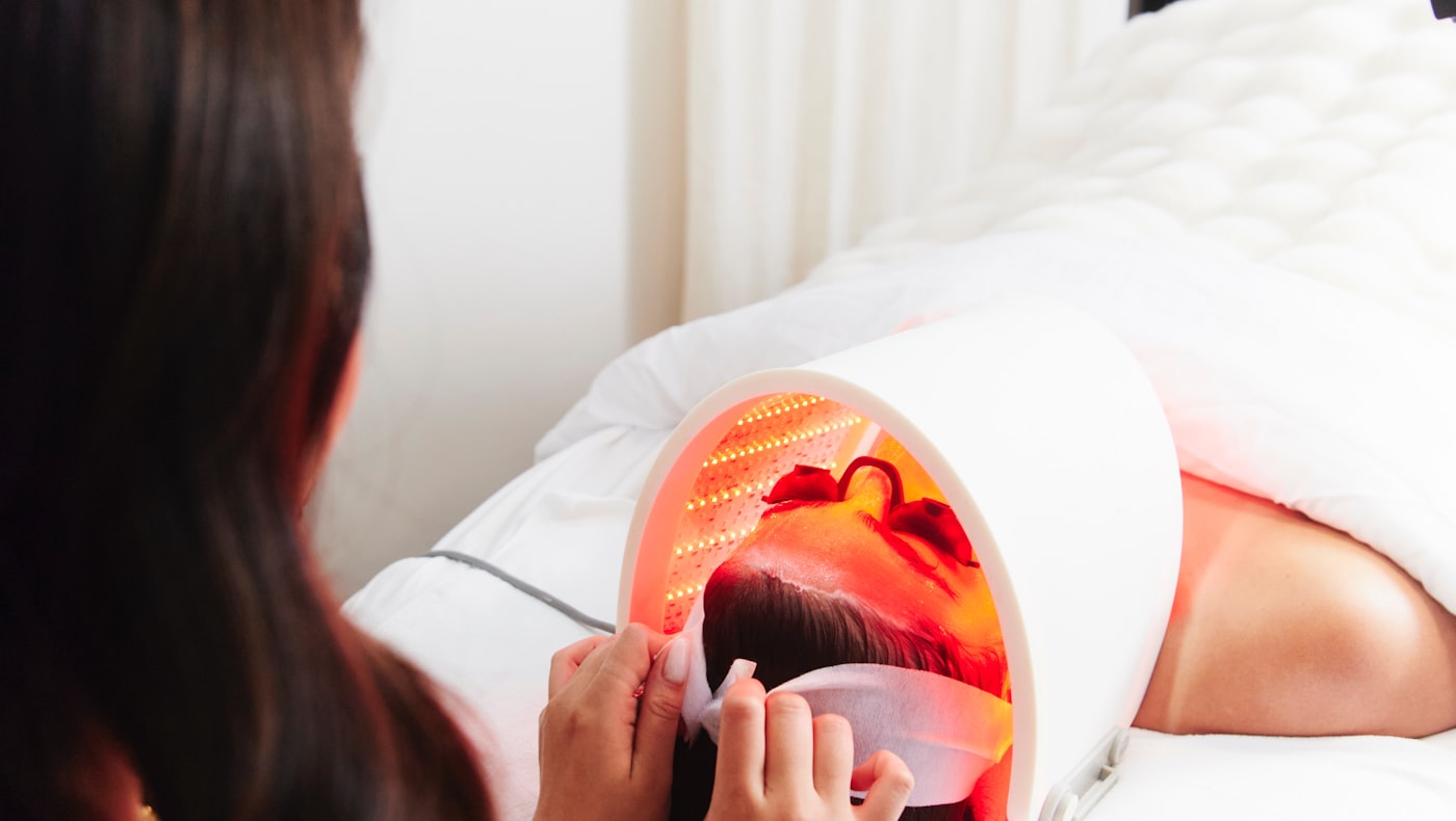 Red light therapy session with a woman lying under a red LED panel